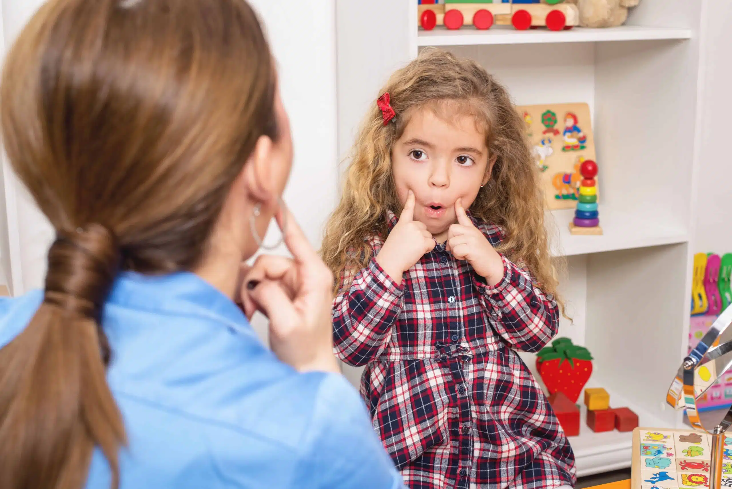Young girl in speech therapy office. Preschooler exercising correct mouth form for sounds